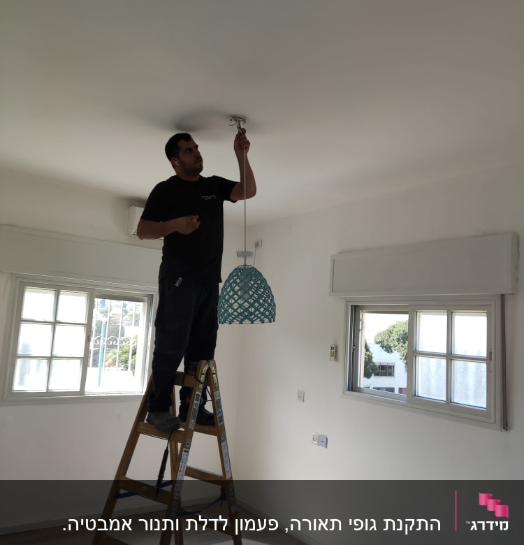 חשמלאי מתקין מנורה מהתקרה בעזרת סולם